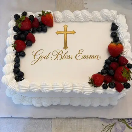 White sheet cake with berries and a cross