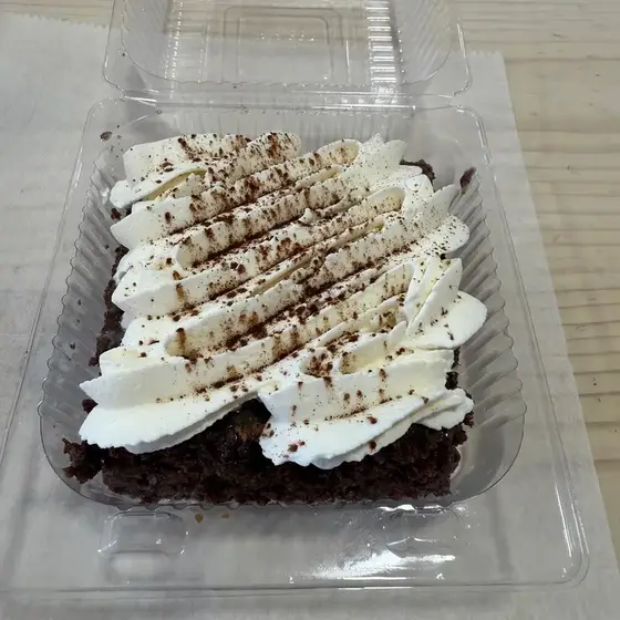 Chocolate brownie with whipped cream and a chocolate drizzle