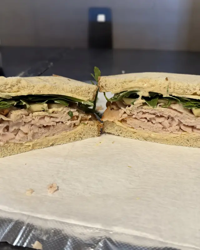 A turkey sandwich with greens on fresh bread